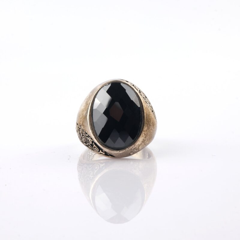 Faset kesim siyah taşlı gümüş erkek yüzük, oval taş formu, yan yüzeylerde kıvrımlı desenler ve eskitme gümüş görünümüyle Ateş Premium.