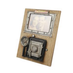 Vintage fotoğraf makinesi tasarımlı, ahşap zemin üzerine metal kamera detayları bulunan dekoratif fotoğraf çerçevesi.