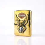 Orijinal Zippo Armor çakmak, gold gövdesi, Harley-Davidson teması, kartal ve kurukafa detaylı kabartmalı tasarımıyla öne çıkan kalın gövdeli premium Zippo çakmak modeli – Ateş Premium Armor Zippo koleksiyonu.