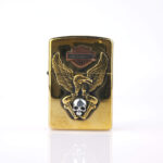 Orijinal Zippo Armor çakmak, gold gövdesi, Harley-Davidson teması, kartal ve kurukafa detaylı kabartmalı tasarımıyla öne çıkan kalın gövdeli premium Zippo çakmak modeli – Ateş Premium Armor Zippo koleksiyonu.